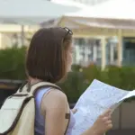 Solo traveler reading a city map with a backpack