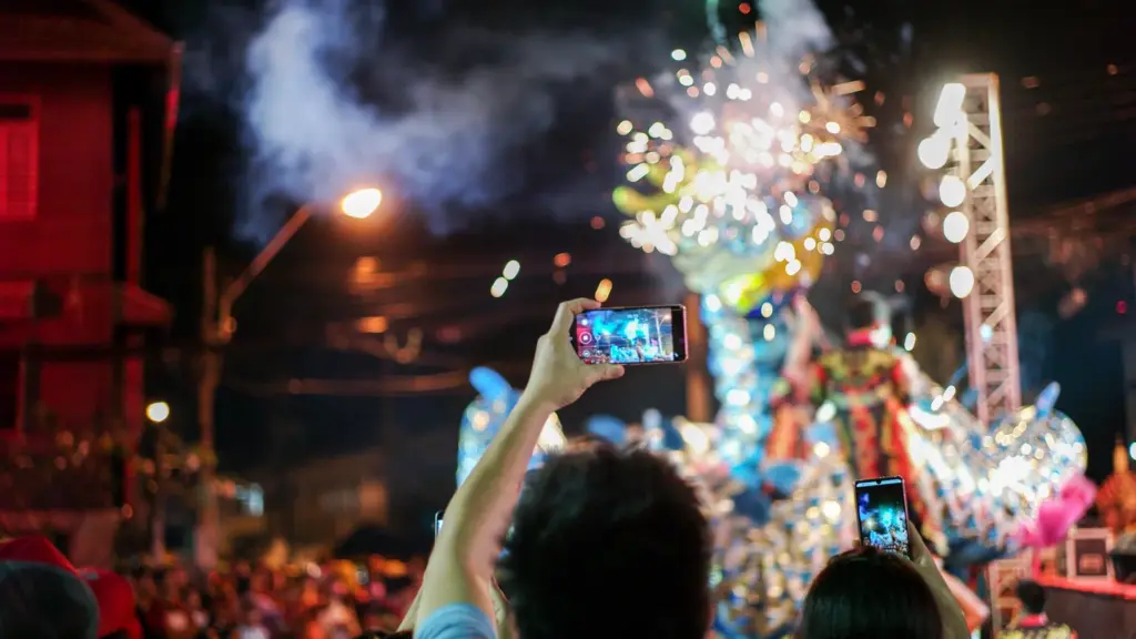 Festival spectators recording a dragon dance and fireworks at night