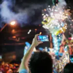 Festival spectators recording a dragon dance and fireworks at night