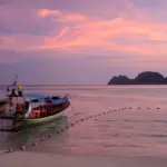 Longtail boats beside a Thai island beach at sunset